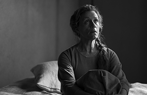 Macbeth McDormand 0106 Francis McDormand as Lady Macbeth sitting on a bed with with her knees bent up to her torso, wearing night dress, pillow in the background (black and white photograpm).